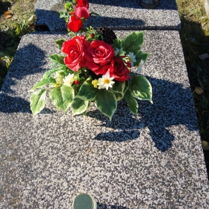 Zdjęcie przedstawia wiązankę sztucznych kwiatów na grobie zmarłego podopiecznego Naszego Domu.